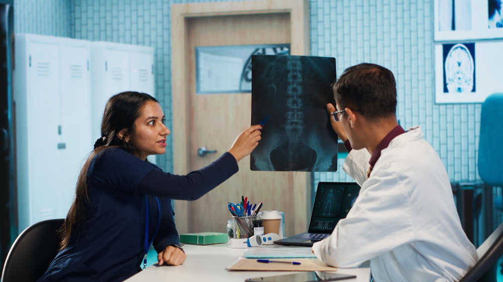 Cost of Minimally Invasive Spine Procedures Explained Doctor reviewing spinal imaging with a patient while discussing minimally invasive spine procedure options and costs